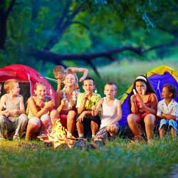 Summer Camp Kids and Staff Roasting Marshmallows by Campfire